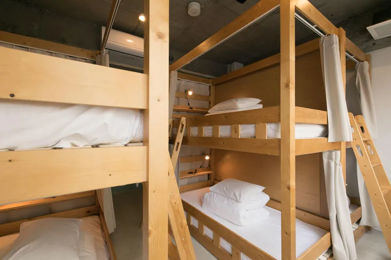 Two-tier wooden bunk beds, each with a curtain and a reading light