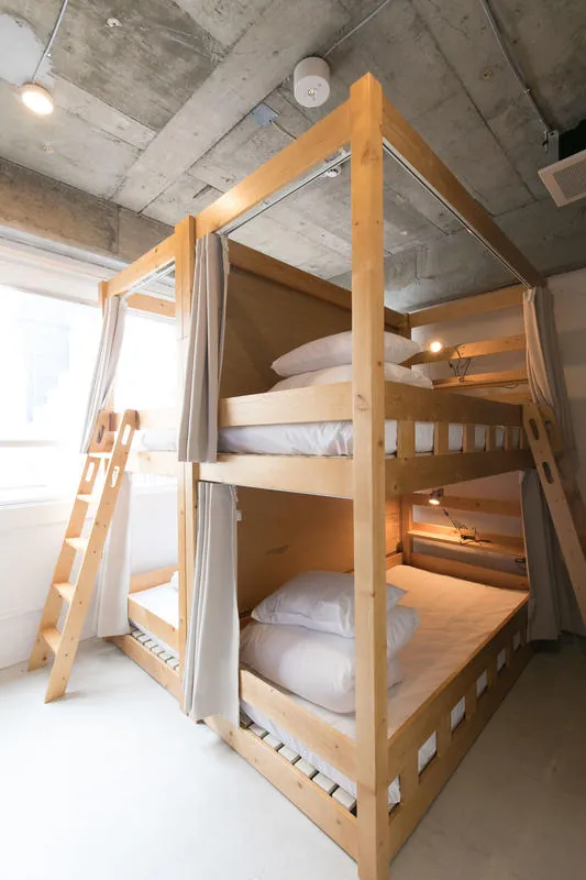 A two-tier wooden bunk bed with ladders and curtains