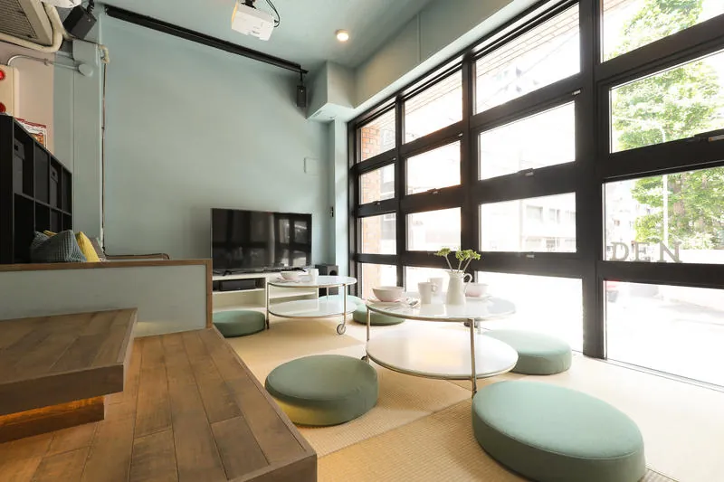 Lounge with sage-green walls, low round tables and floor cushions by a large window