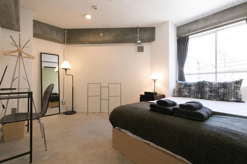 Private room with a double bed, a floor lamp and a large window